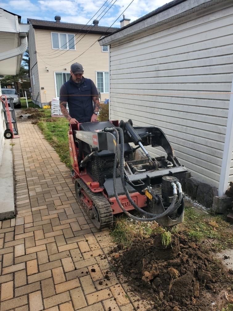 Webcor Contracting employee using machine to dig for a fence post install.