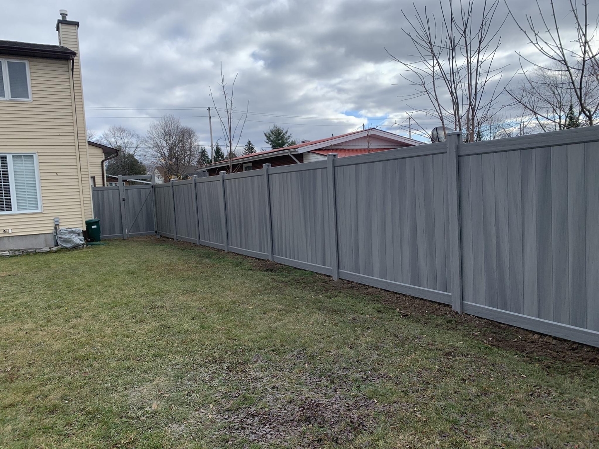 Grey fence running length of backyard with gate at side of house